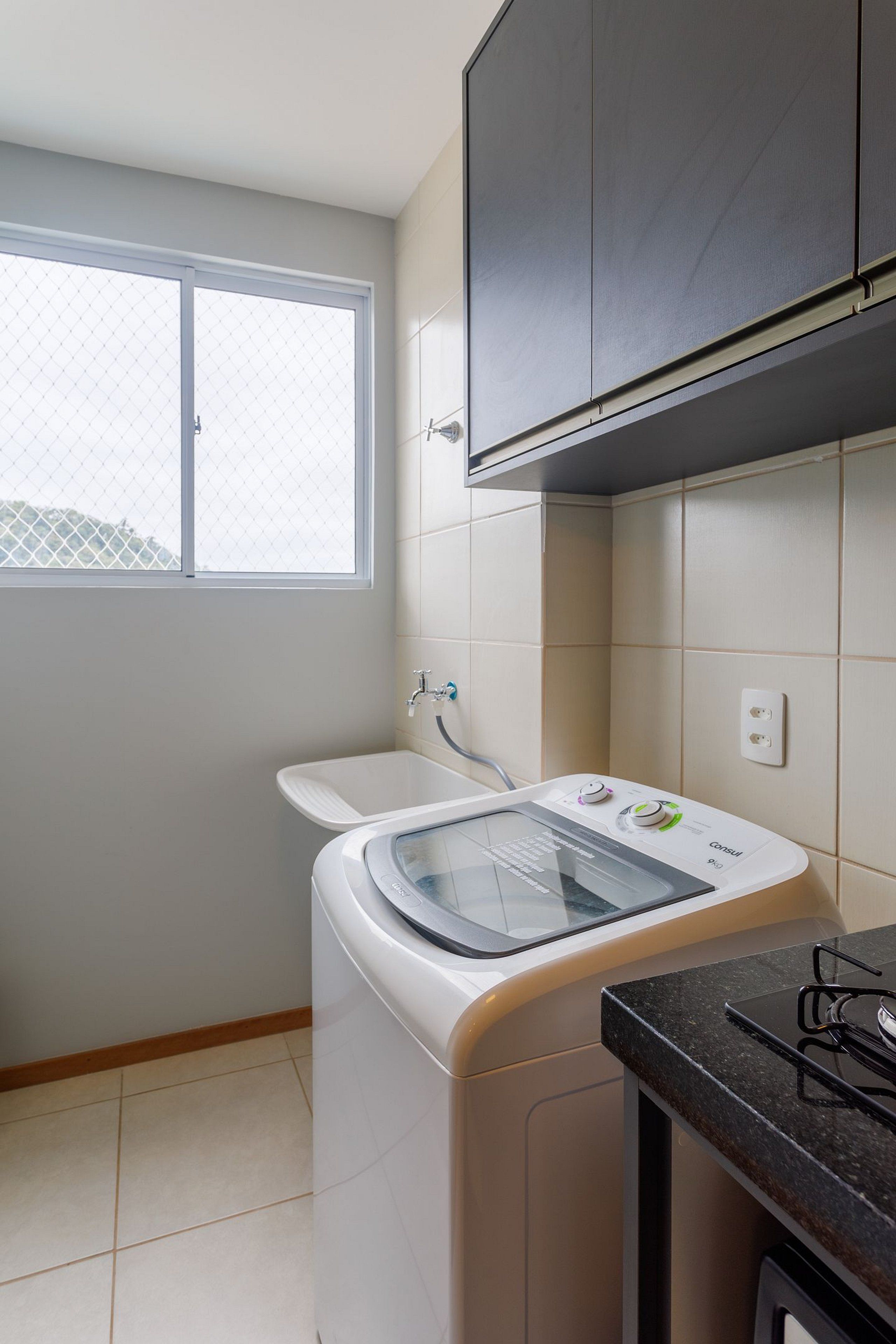 A compact kitchen with a washing machine, a window, and a countertop.