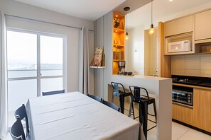 Una cocina moderna con comedor, vista a través de un ventanal y un estante empotrado con utensilios de cocina.