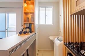 Una cocina compacta con cafetera, lavabo y ventana.