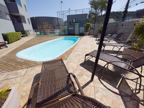 A swimming pool with lounge chairs and a wooden deck. - Curta Praia do Quilombo - Lunata (Penha)