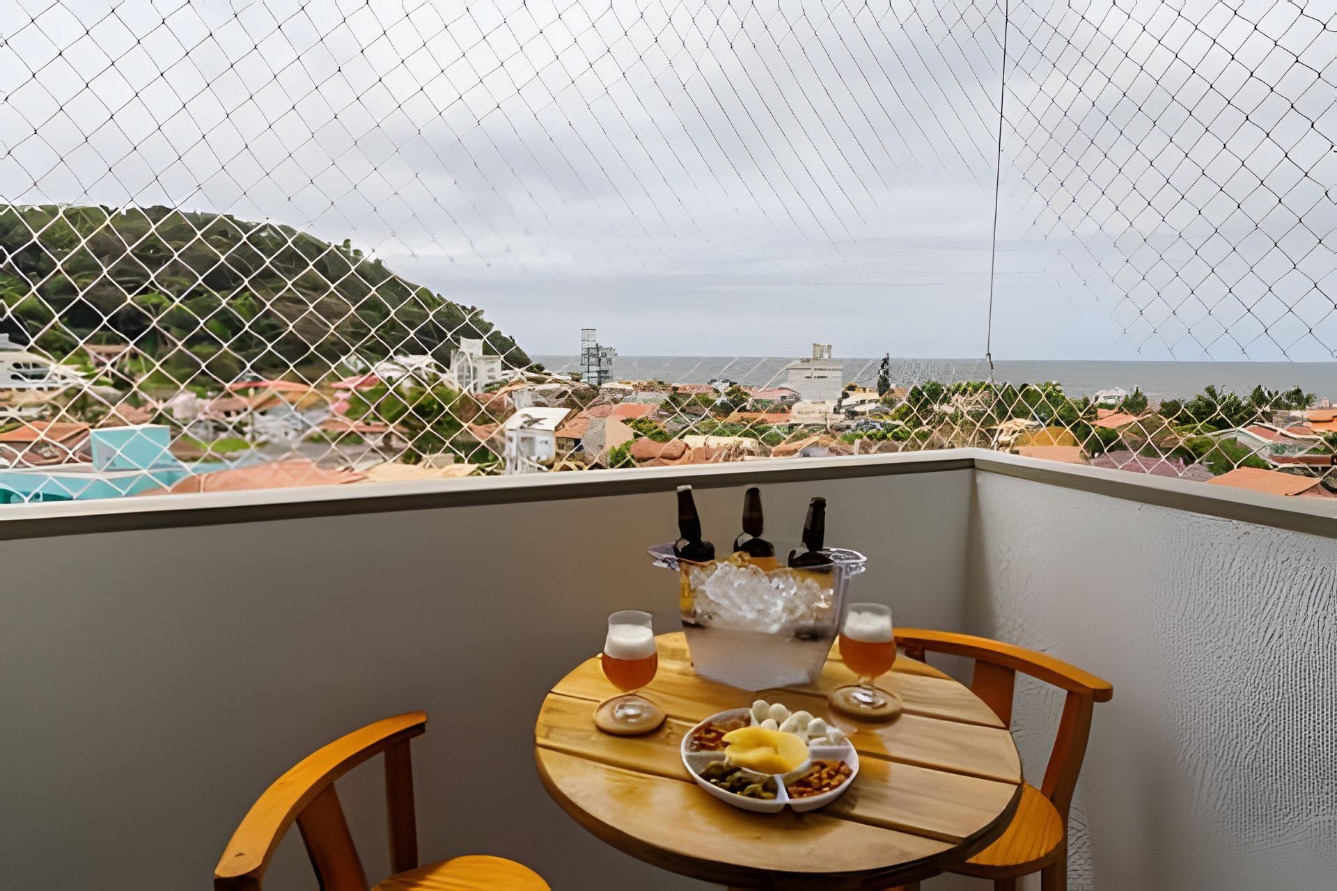 Uma varanda com uma mesa posta para dois, uma tigela de comida e duas cervejas.
