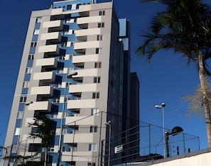 Un edificio de gran altura con varios balcones, cielo despejado y una farola.