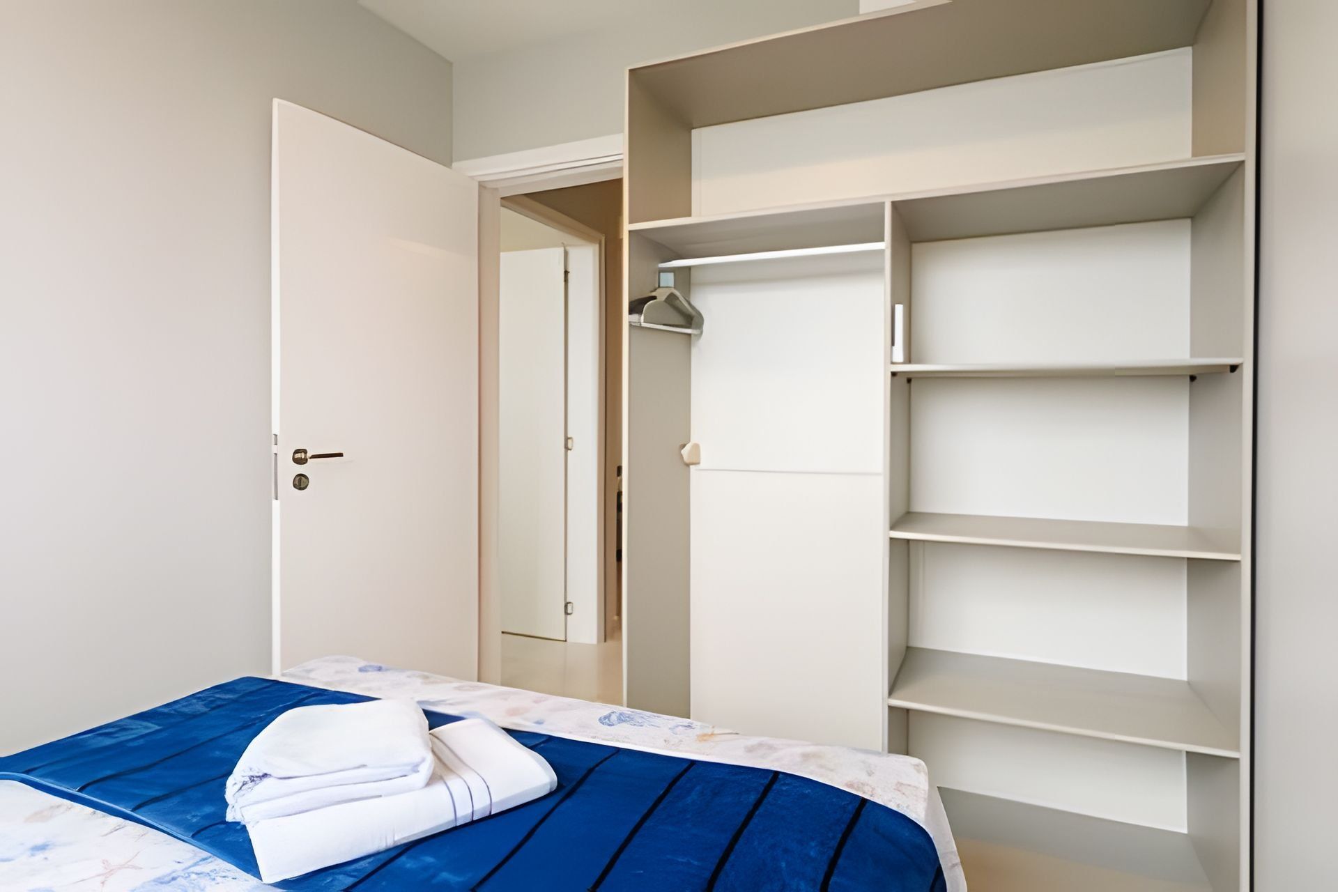 A bedroom with a bed, a wardrobe, and a door.