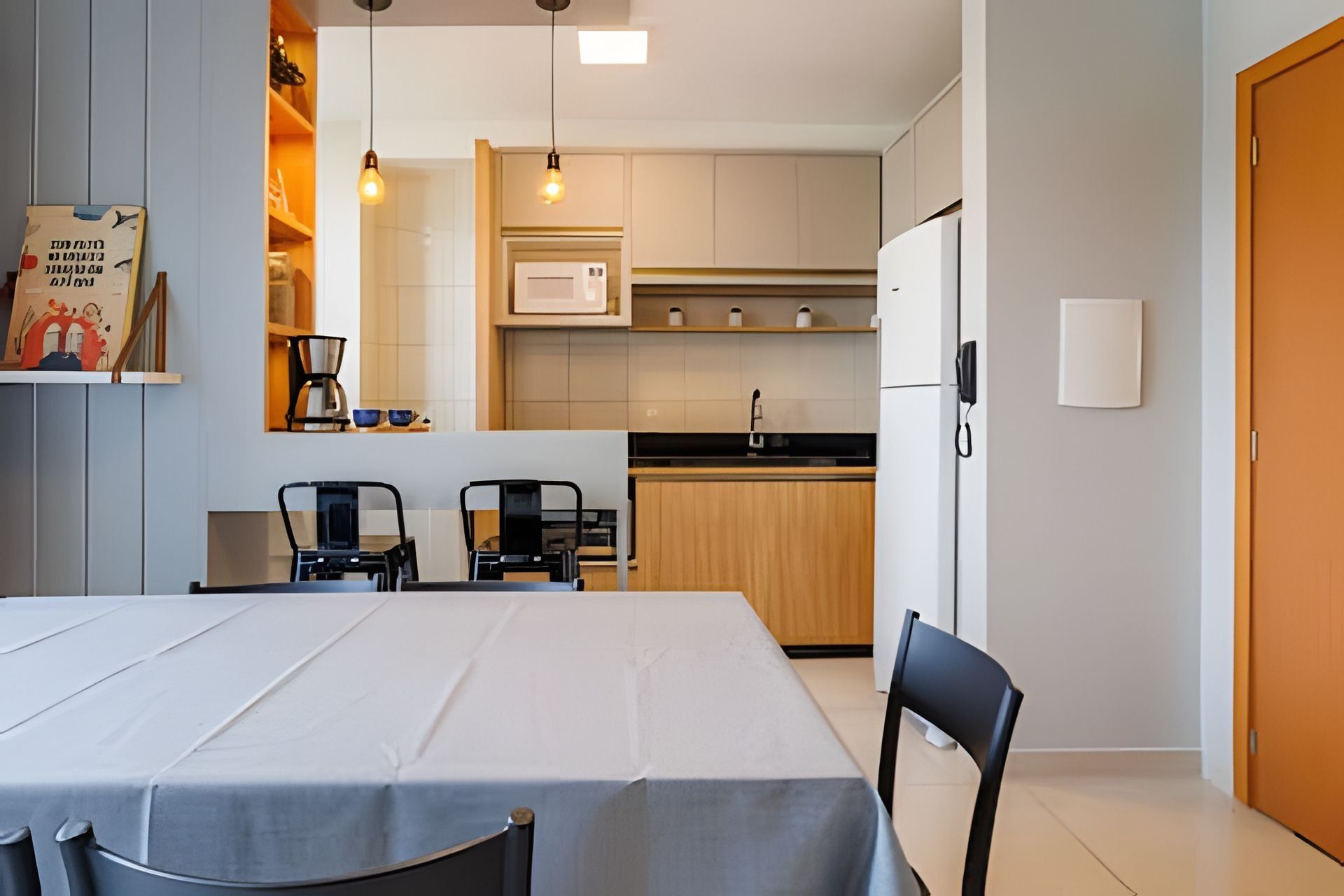 A modern kitchen with a dining area, including a table with chairs, a microwave, and a refrigerator.