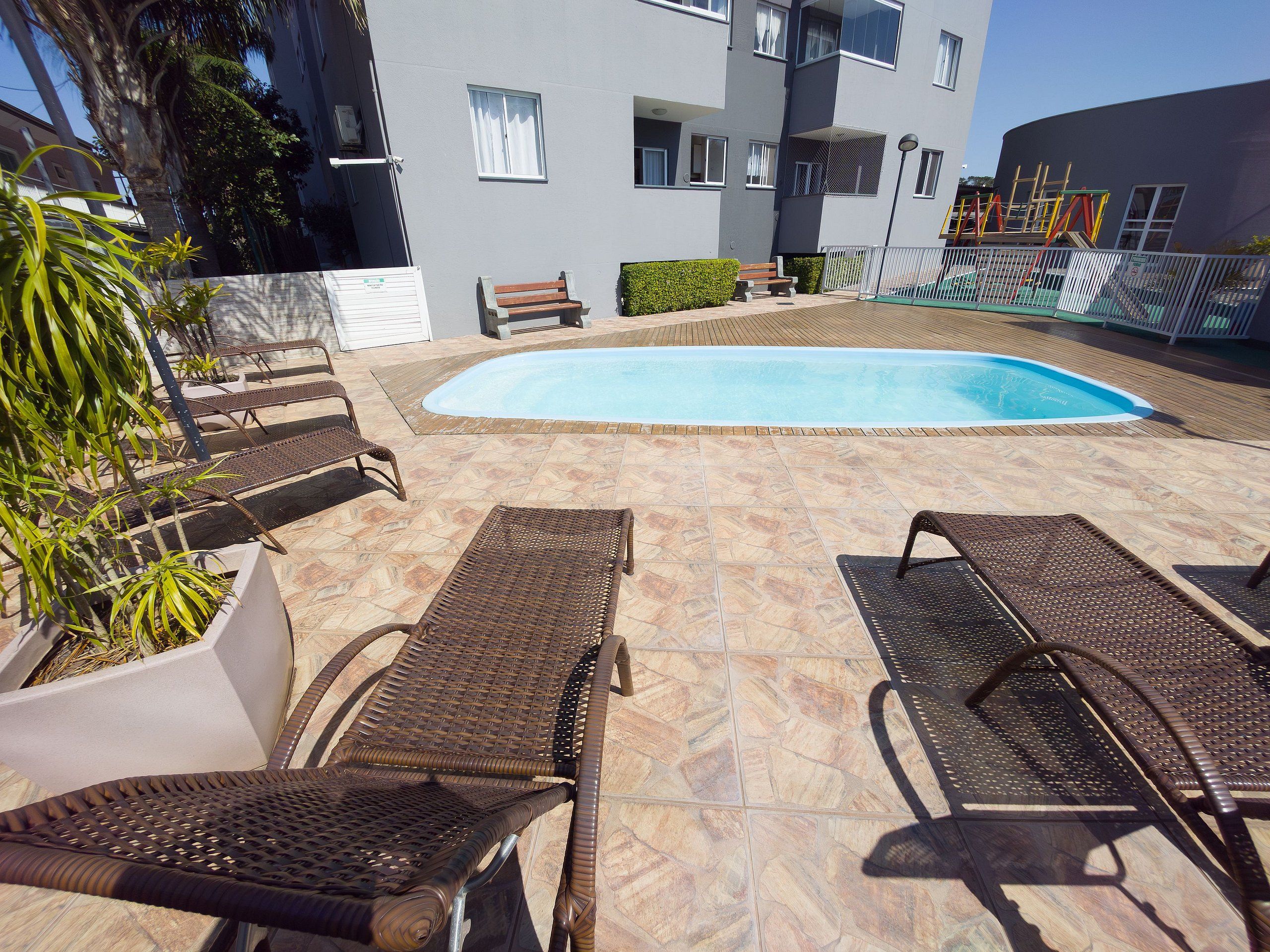A pool area with lounge chairs, a small pool, and a building in the background.