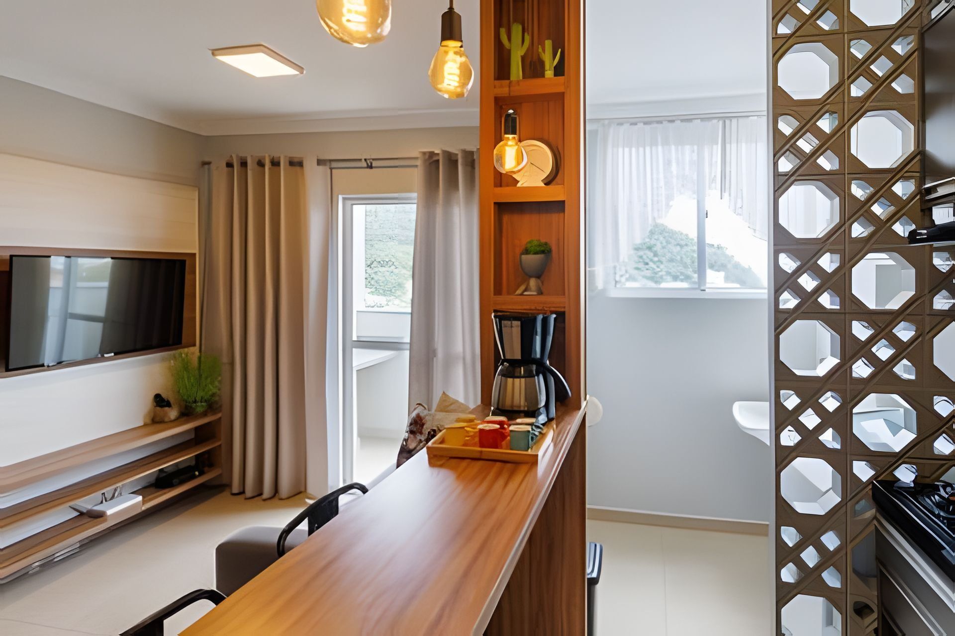 A modern kitchen with a wooden countertop, a coffee maker, and a TV mounted on the wall.