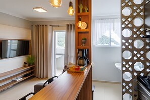 Une cuisine moderne avec un plan de travail en bois, une machine à café et un téléviseur fixé au mur.