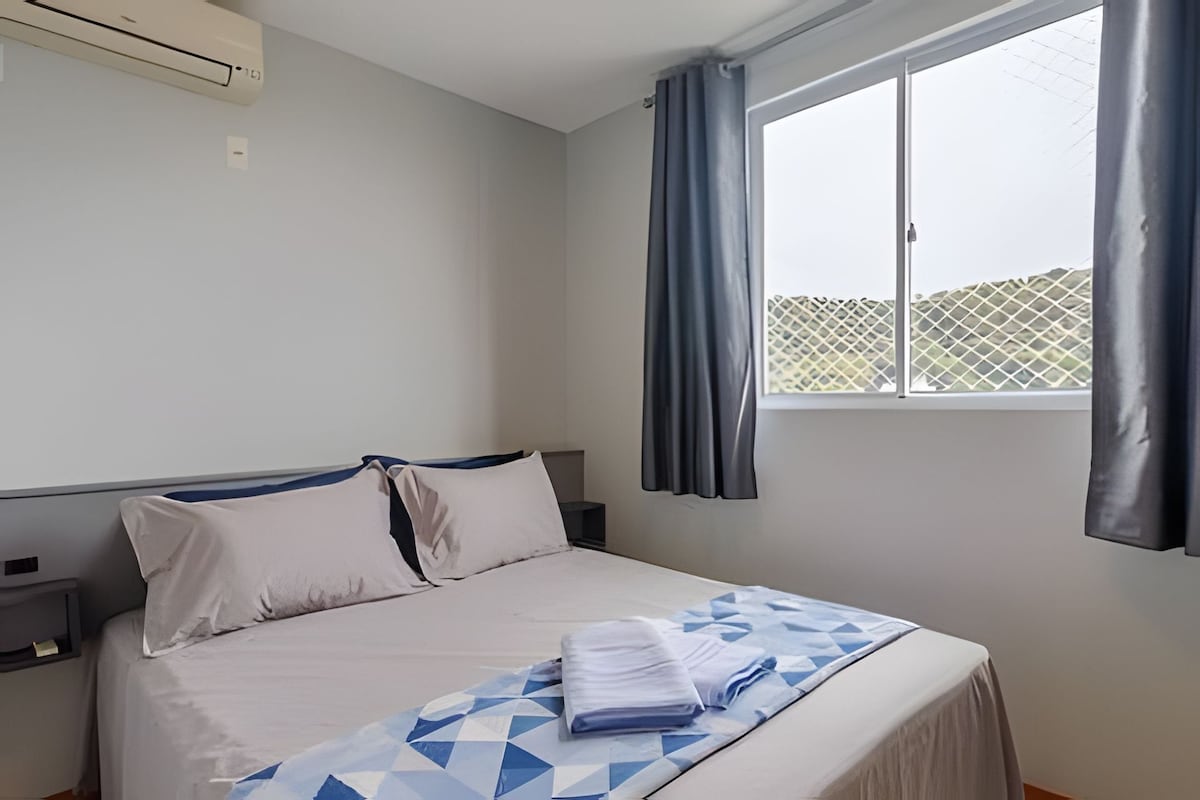 A bedroom with a bed, a window, and a curtain.