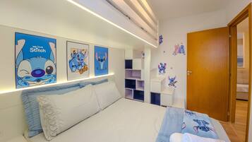 Un dormitorio con cama, mesita de noche y decoración en la pared, incluyendo a Stitch.