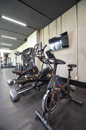 A row of stationary bikes in a gym with a flat-screen TV on the wall. - Zona Purísima y CAS - ¡5 camas, GYM y alberca! (Monterrey)