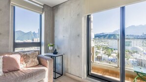 Un salon moderne avec un canapé, une petite table d’appoint et de grandes fenêtres donnant sur la ville.