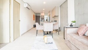 Un salon moderne comprenant un canapé, une table à manger avec des chaises, un coin cuisine et un couloir.