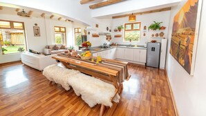 A spacious kitchen with wooden beams, a dining table, and a bench.