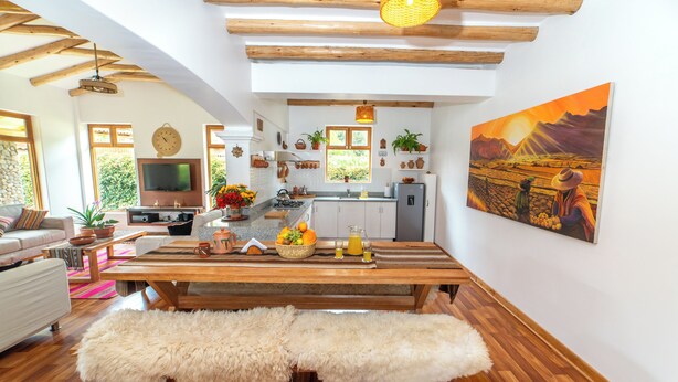 A modern living room with a wooden dining table, a white sofa, and a fluffy bench.