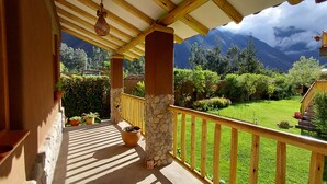 A balcony with a stone pillar, wooden railing, and potted plants.