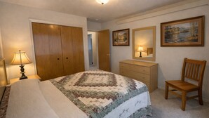 A bedroom with a bed, dresser, chair, and two framed pictures on the wall. - Rocky Cliff 3 bedroom/2 bath home located in the town of Hill City! (Hill City)