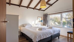 Una camera da letto con un letto, un comodino, una finestra e una lampada a sospensione.
