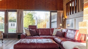Un divano modulare in pelle rossa con una coperta bianca, un termosifone e vista sull'esterno attraverso ampie finestre.