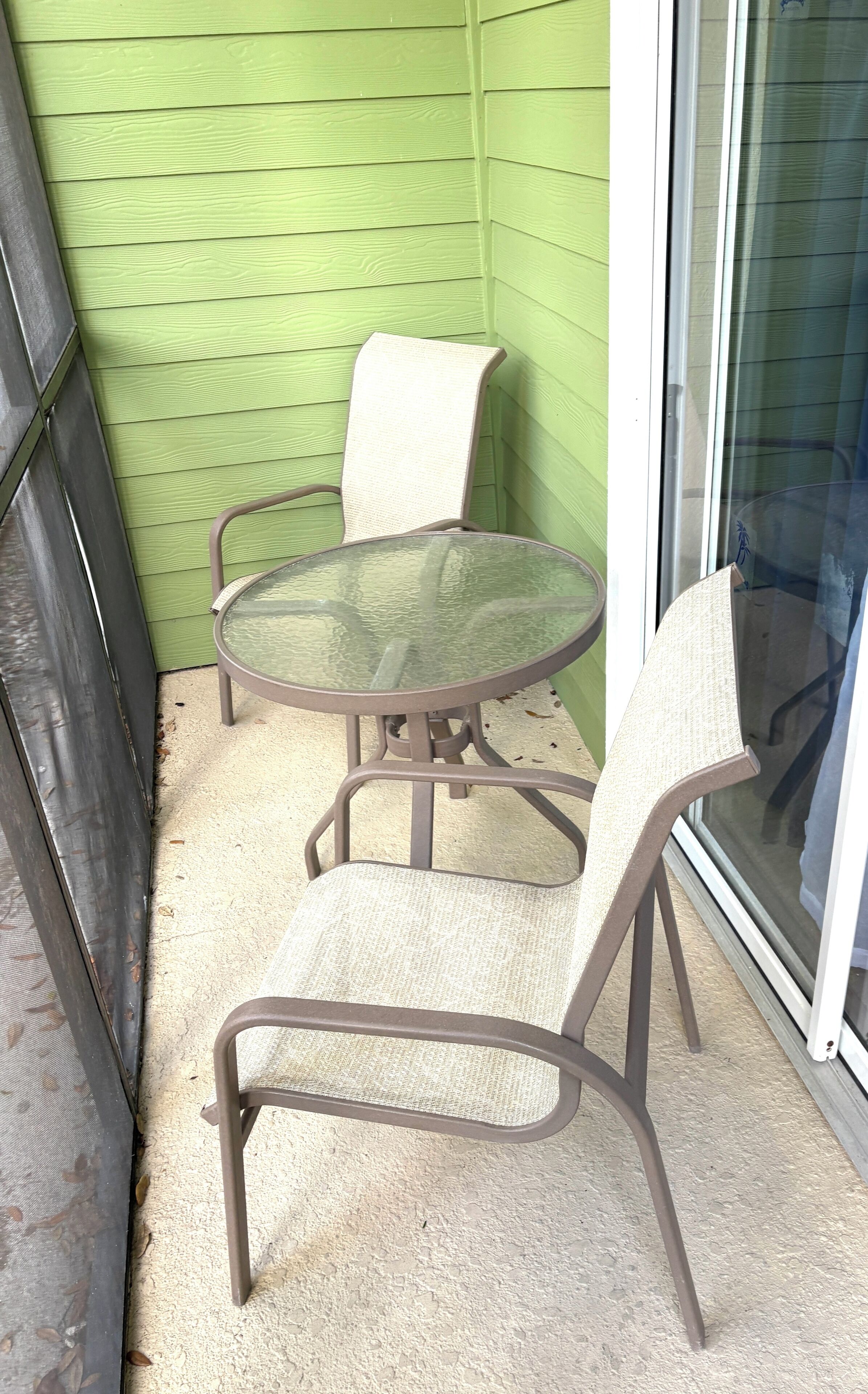 Eine kleine Patio-Terrasse mit einem runden Glastisch und zwei Stühlen.