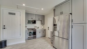 A modern kitchen with stainless steel appliances, grey cabinets, and a tiled floor. - Cozy Coachella Valley Home! Golf, Shop + Dine (Indio)