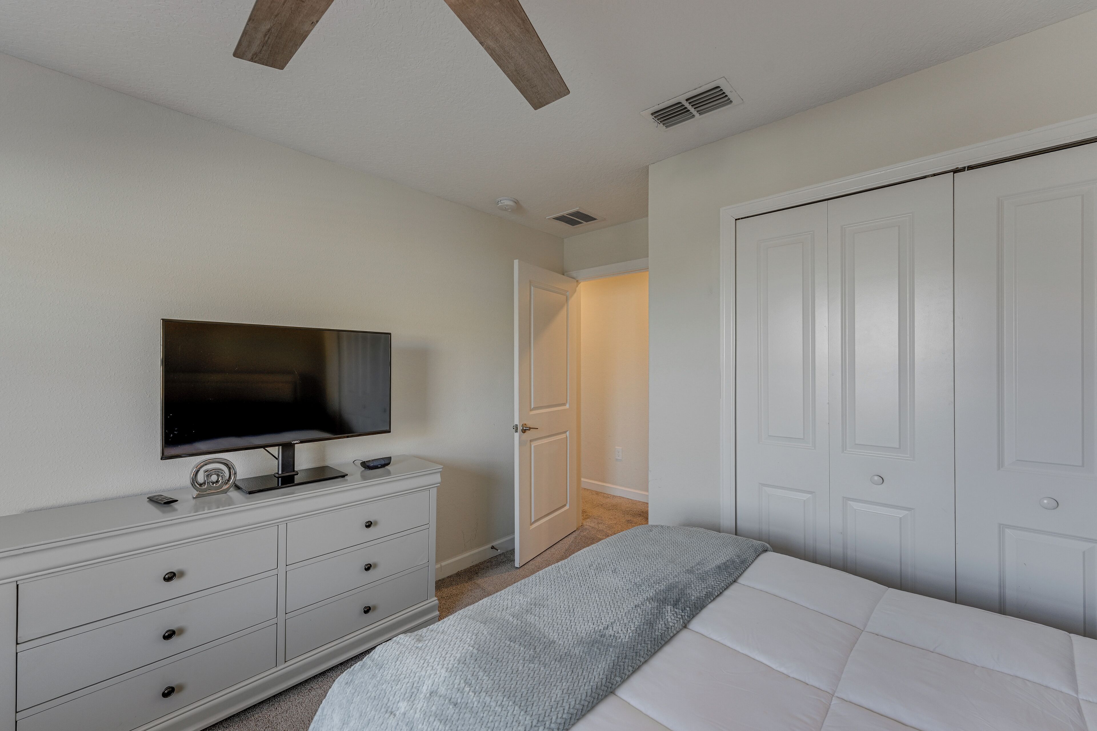 Ein Schlafzimmer mit Bett, Kommode, Fernseher und Schrank.