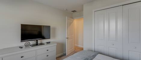 Ein Schlafzimmer mit Bett, Kommode, Fernseher und Schrank.