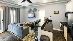 A modern kitchen with a black countertop, white cabinets, and a stainless steel refrigerator. - Steps to the Beach Great Value Pool Home (South Padre Island)