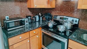 Eine Küche mit Holzschränken, einer Mikrowelle, einer Kaffeemaschine, einem Herd und verschiedenen Küchenutensilien.