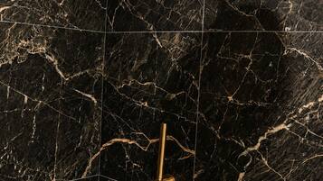 A showerhead and control panel on a black marble wall.