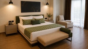 Moderni hotellihuone, jossa on suuri sänky, yöpöydät, penkki ja näkymä ulos.