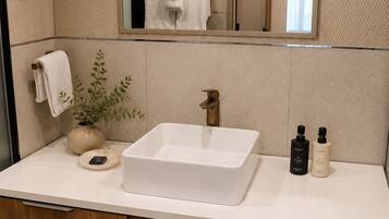 A modern bathroom with a large rectangular sink, a mirror above it, and a wooden cabinet below.