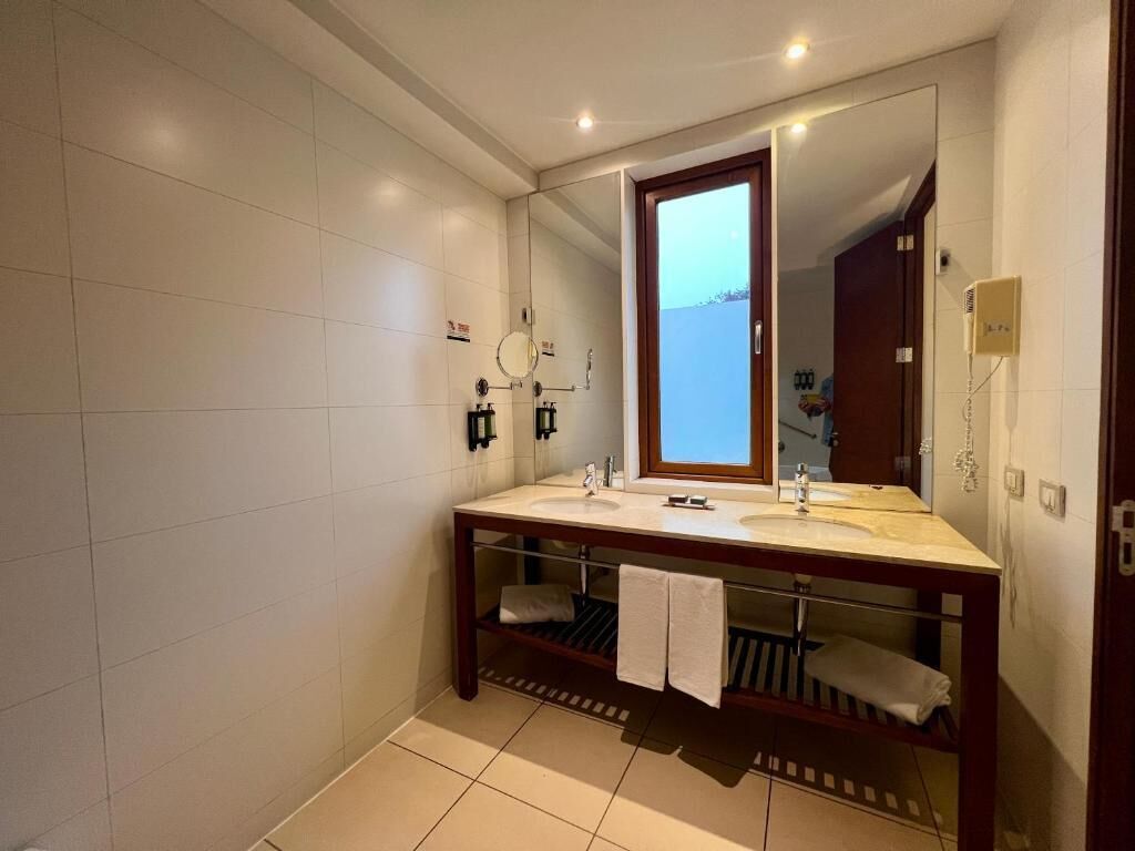 Un baño moderno con dos lavamanos, un espejo grande y un perchero para toallas.