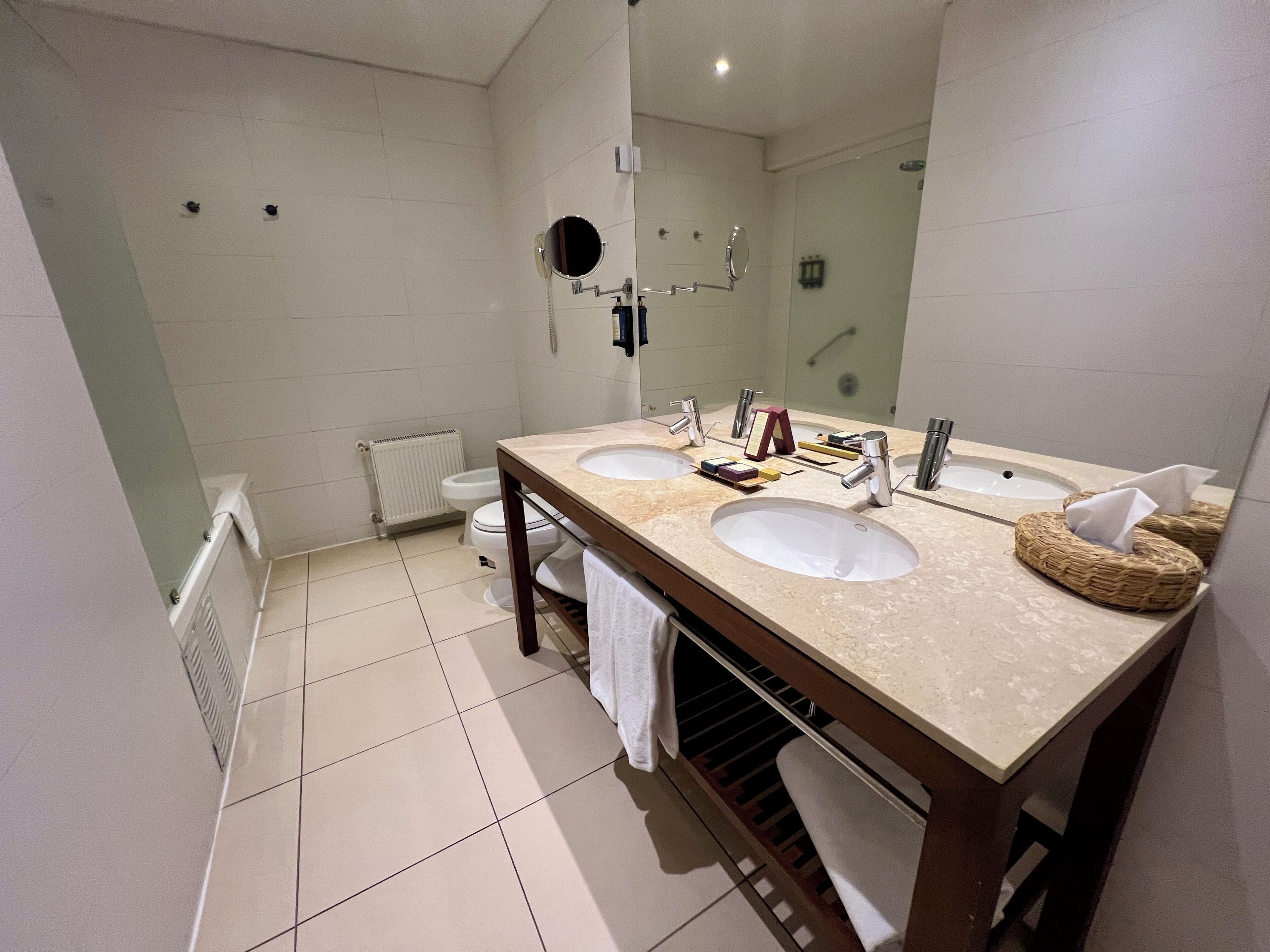 Baño con dos lavamanos, un espejo, inodoro y ducha.