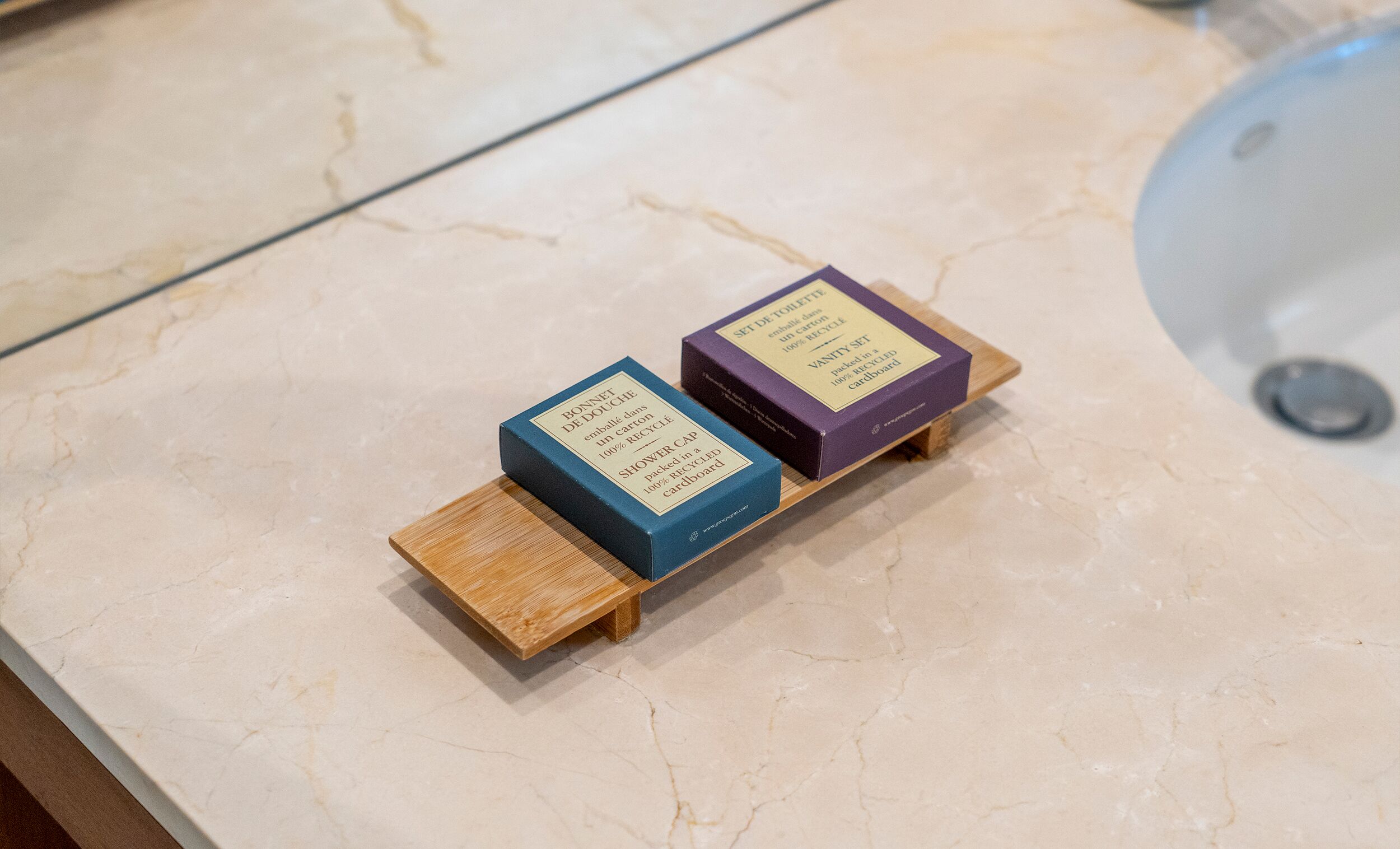 Two boxes on a marble surface, one labeled 'BONNET DE DOUCHE' and the other 'VANITY SET'.