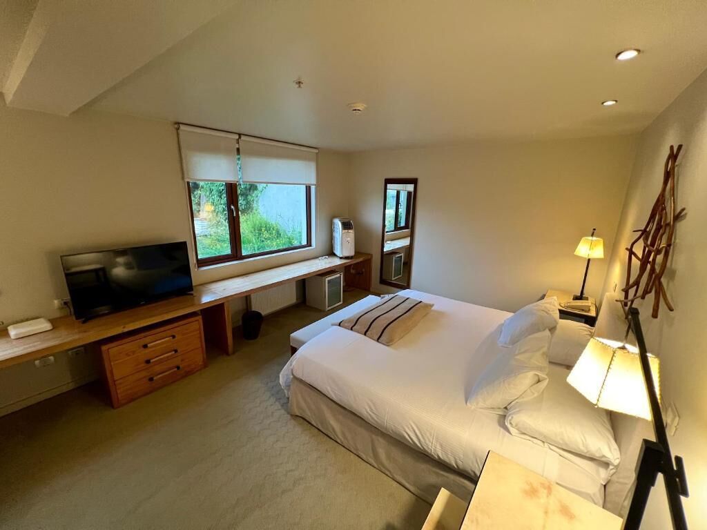 Quarto com cama, televisão, escrivaninha e janela.