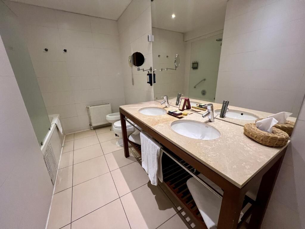 Ein modernes Badezimmer mit zwei Waschbecken, einem großen Spiegel und einer Duschkabine.