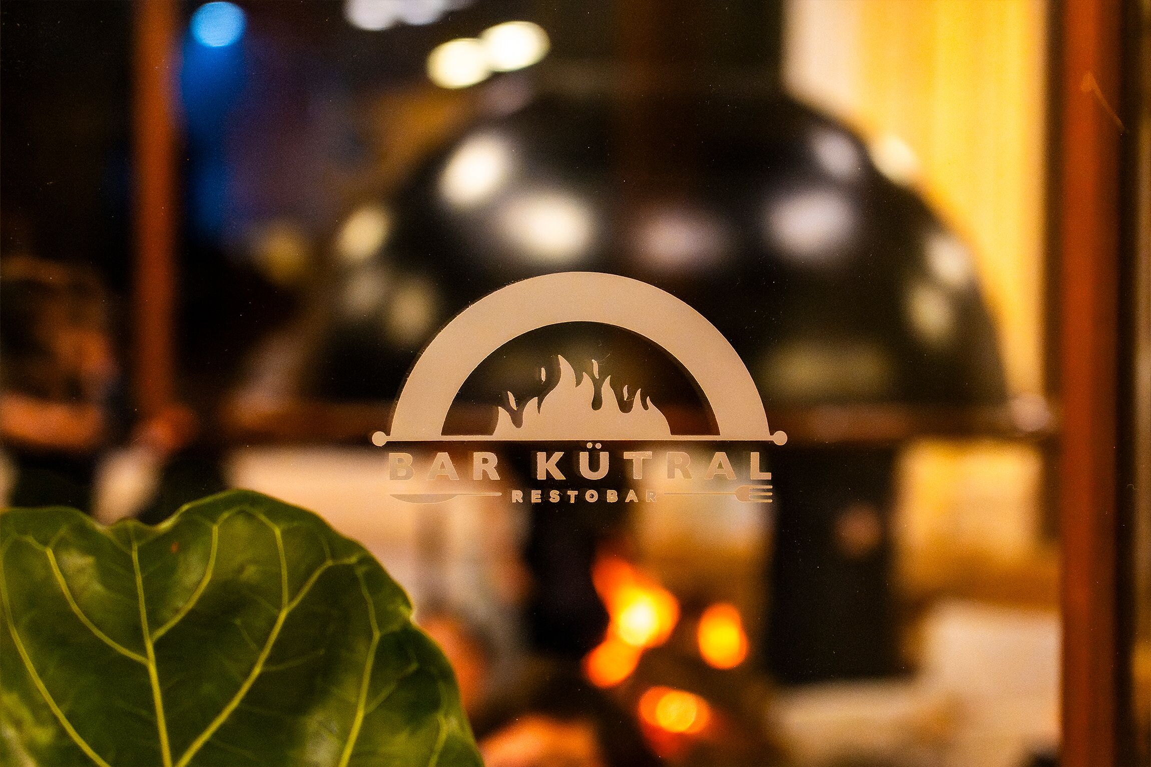 A logo with the text 'BARK KÜTRAL RESTOBAR' on a glass window.