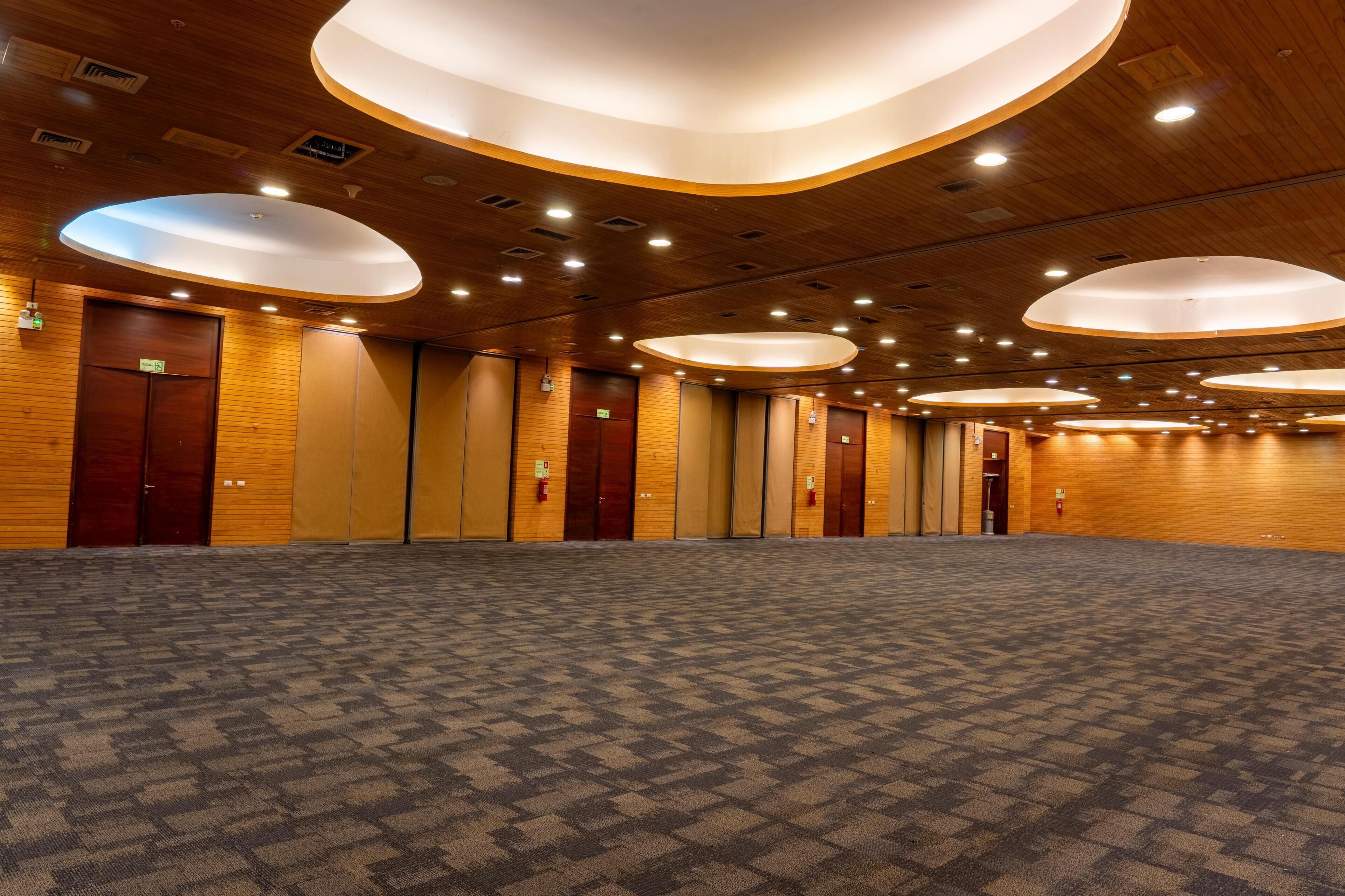 Ein Hotelkonferenzraum mit Teppichboden, Holzwandverkleidung und mehreren Türen.