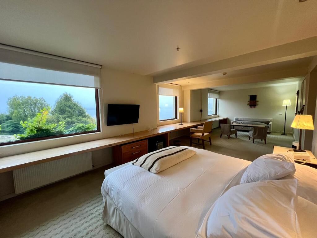 Una habitación de hotel con una cama grande, un escritorio, una silla, un televisor y vistas al exterior.
