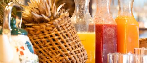 Una mesa con tres botellas de vidrio con líquidos de distintos colores, una cesta tejida y un adorno.