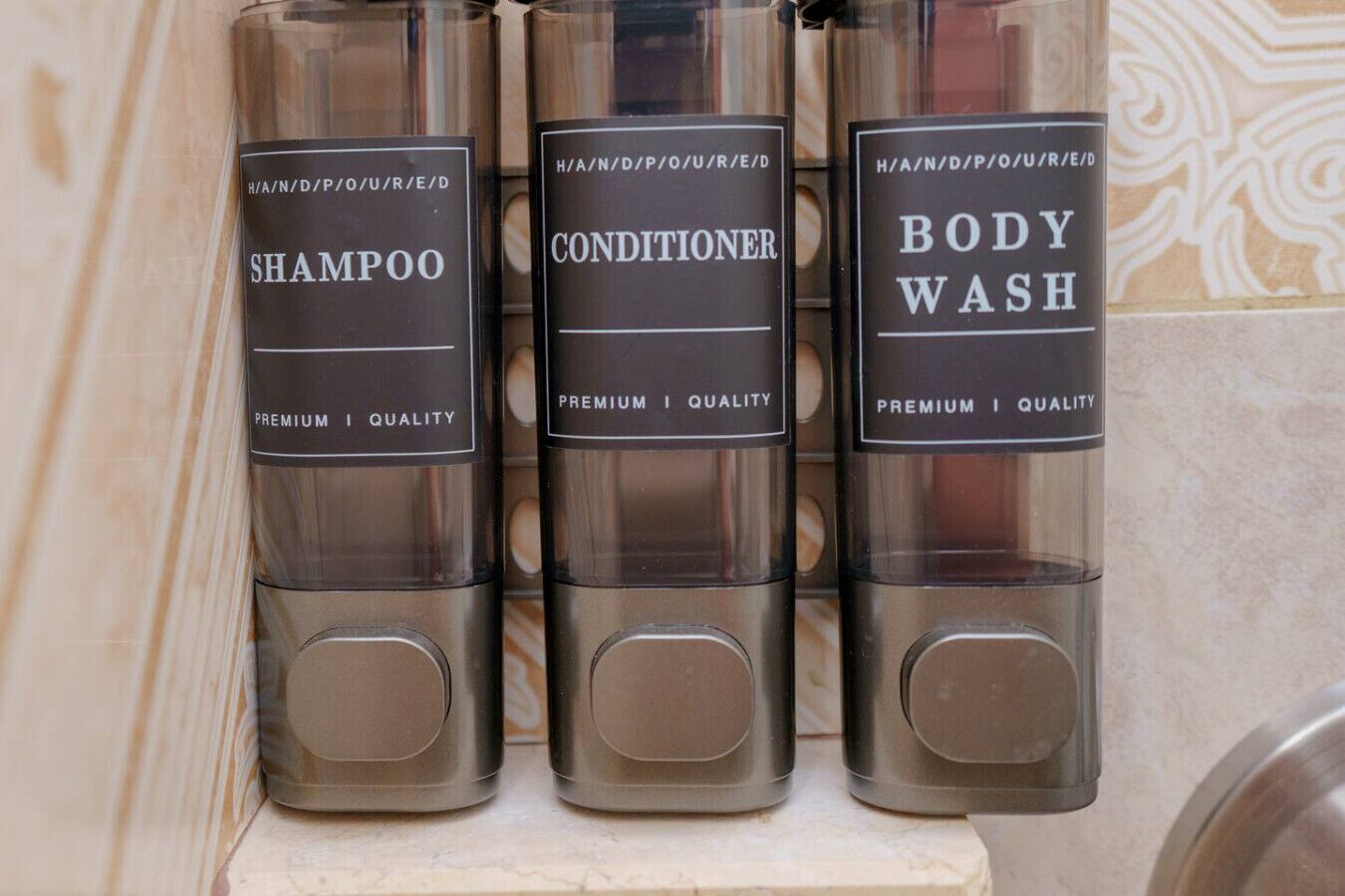 Three bottles of shampoo, conditioner, and body wash on a shelf.