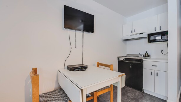 Cocina compacta con televisión de pantalla plana, microondas y lavavajillas.