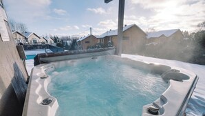 Ein Whirlpool mit schneebedecktem Boden, umgeben von Häusern und einem klaren Himmel.