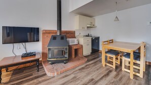 Eine moderne Küche mit integriertem Grill, einem Esstisch mit Stühlen, einem an der Wand befestigten Fernseher und einer Kücheninsel.