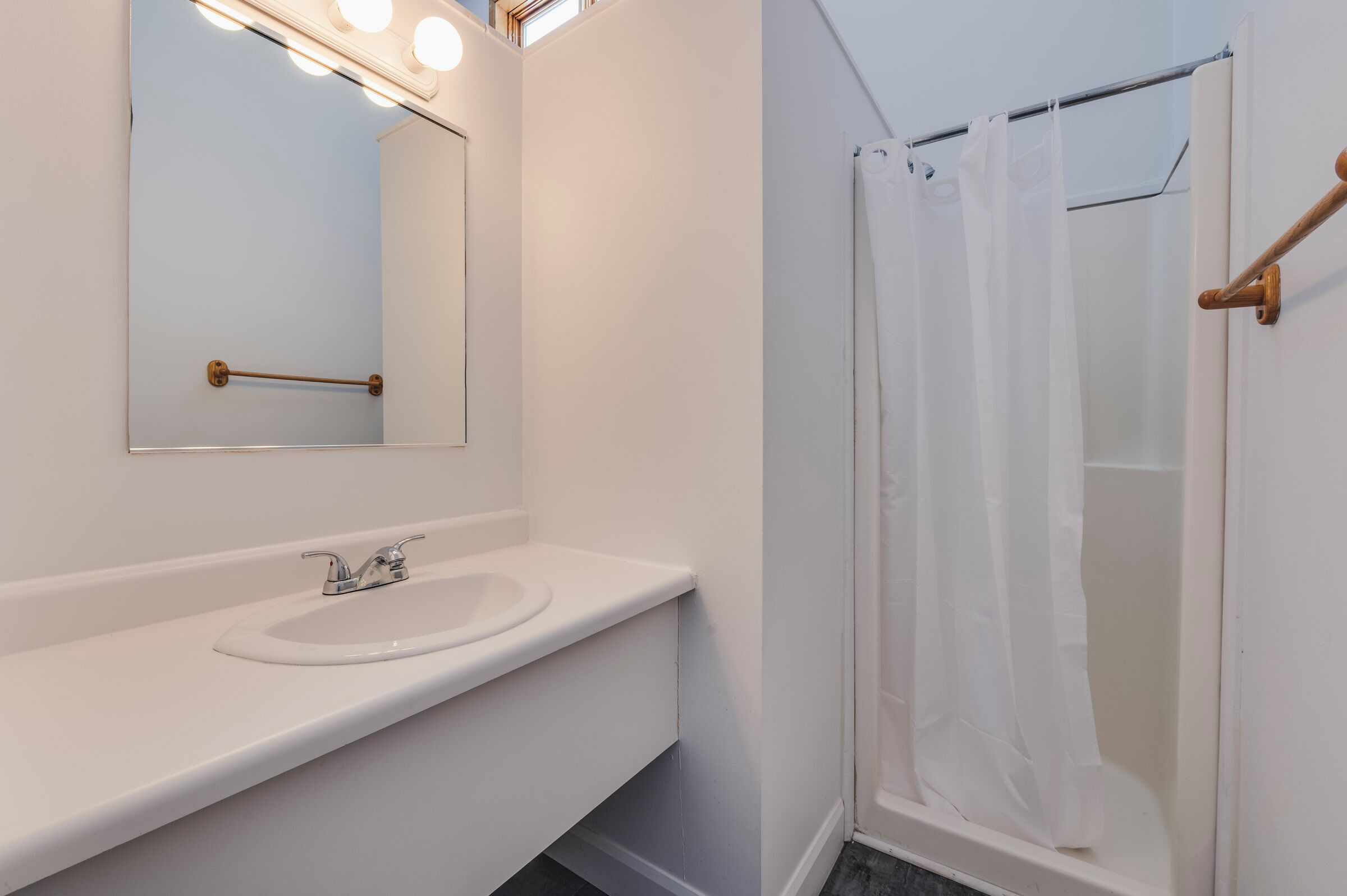 Un baño con lavamanos, espejo y cortina de ducha.