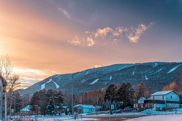 A snow-covered landscape with a mountain, a road, and buildings. - Domaine Mont Sainte-Anne (Saint-Ferréol-les-Neiges)