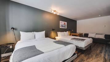 Ein Hotelzimmer mit zwei Betten, einer dunklen Wand, einer Lampe und einem Bergfoto.