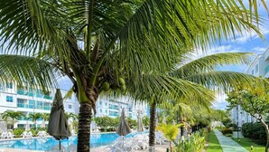 A poolside area with palm trees, lounge chairs, and a swimming pool. - Apto Porto de Galinhas (Ipojuca)