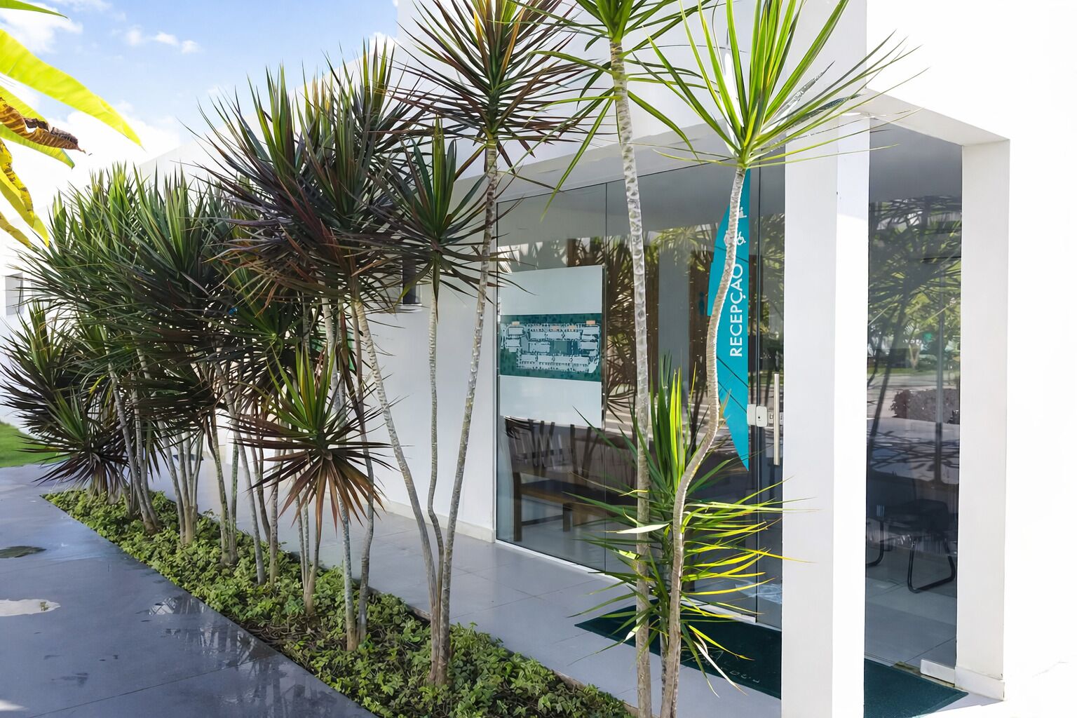 A modern building with a reception area, glass walls, and a sign indicating a reception desk.