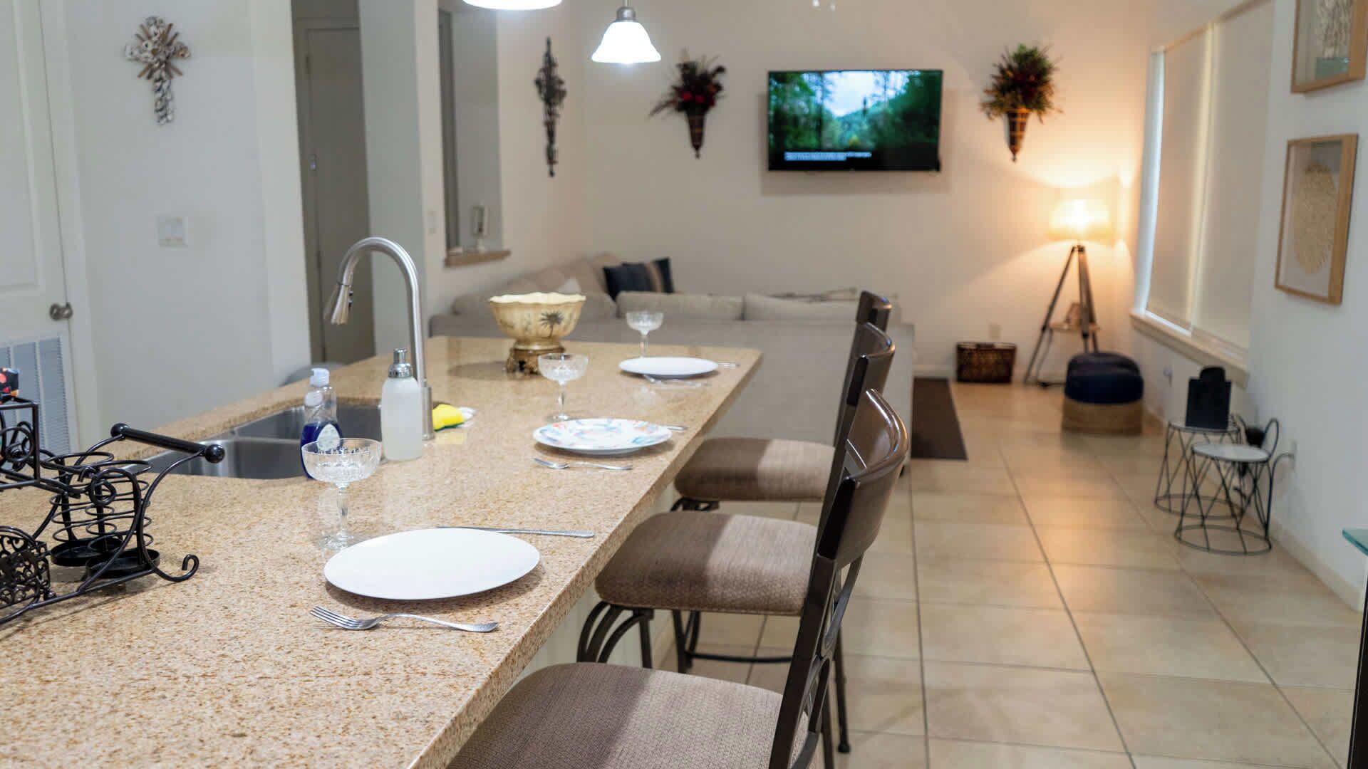 Una cocina moderna con una isla grande, sillas de comedor, un televisor y una mesa para cuatro.